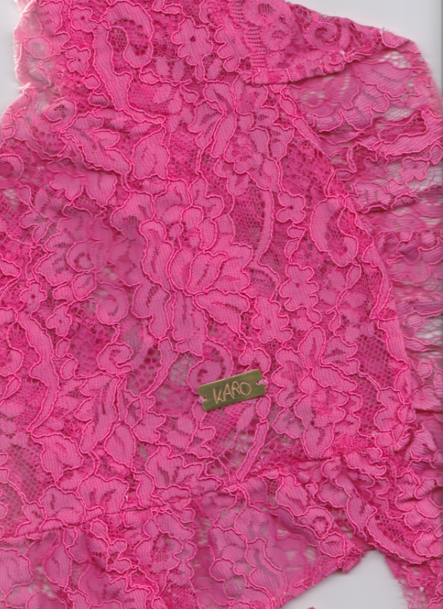 Close-up of pink lace fabric with a brand label.