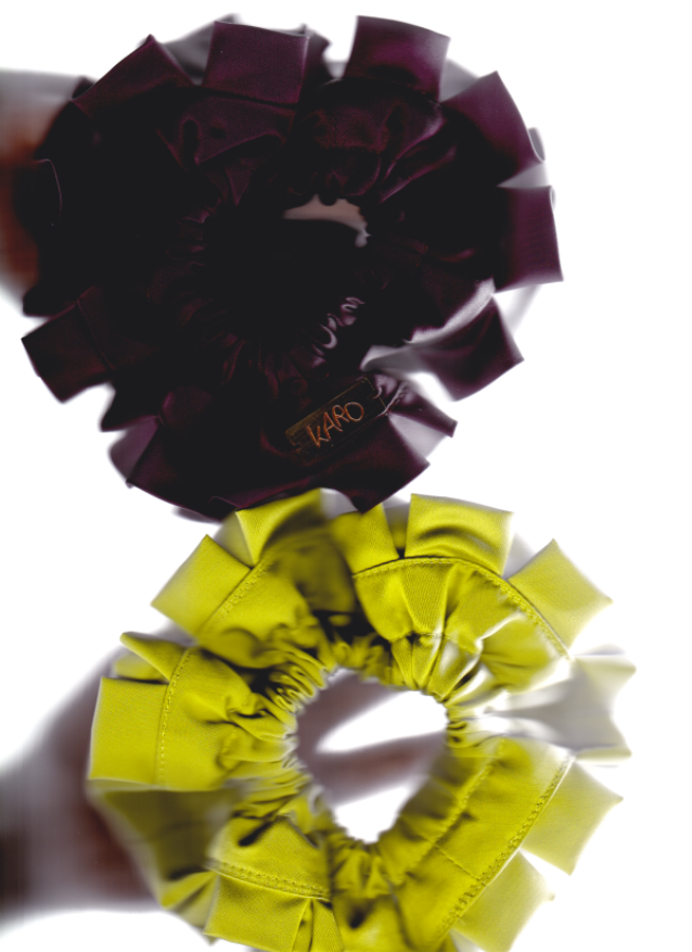 Two hair scrunchies, one purple and one green, on a white background.
