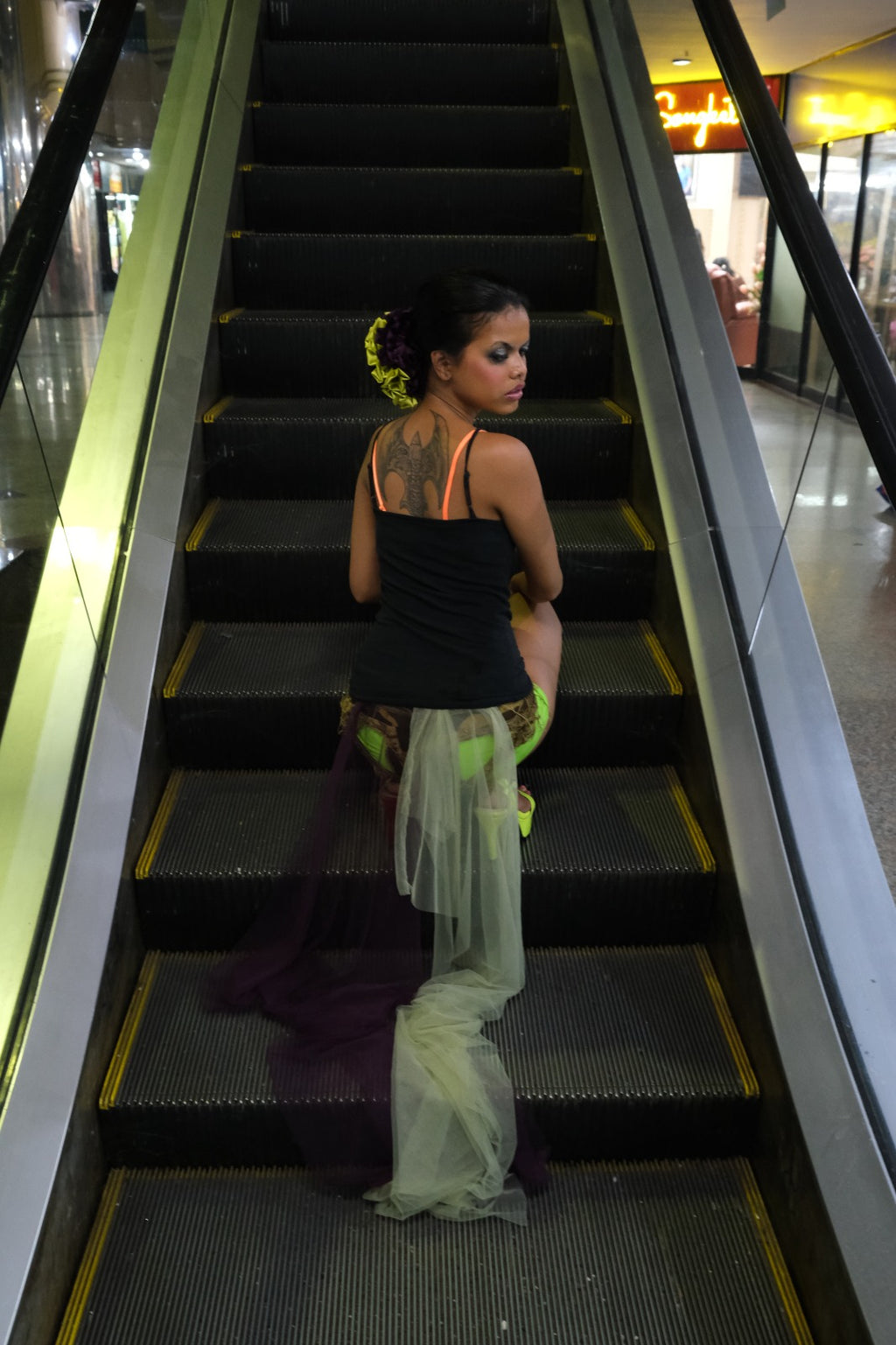 Girl with green and purple scrunchie sitting at mall escalator