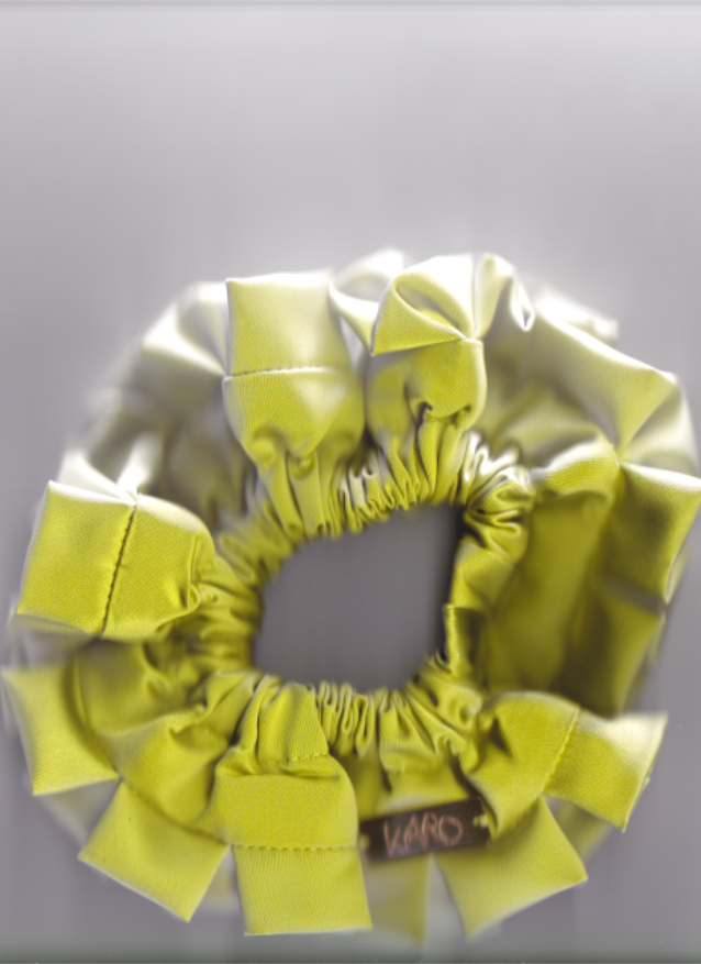 Yellowish green scrunchie with decorative bows on a light gray background