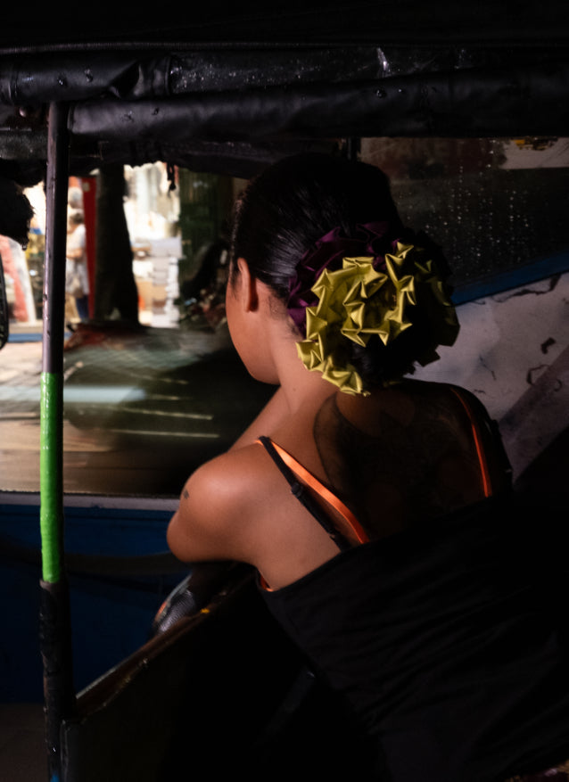 Woman with a green purple flower in her hair on a boat